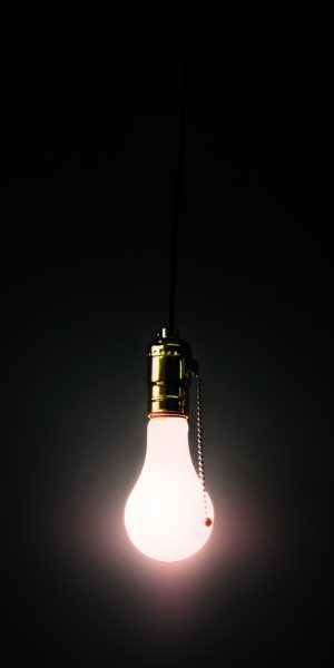 Light bulb hanging against grey background